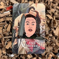 a pin with a picture of a woman with a knife