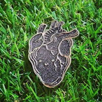 a black enamel heart laying in the grass